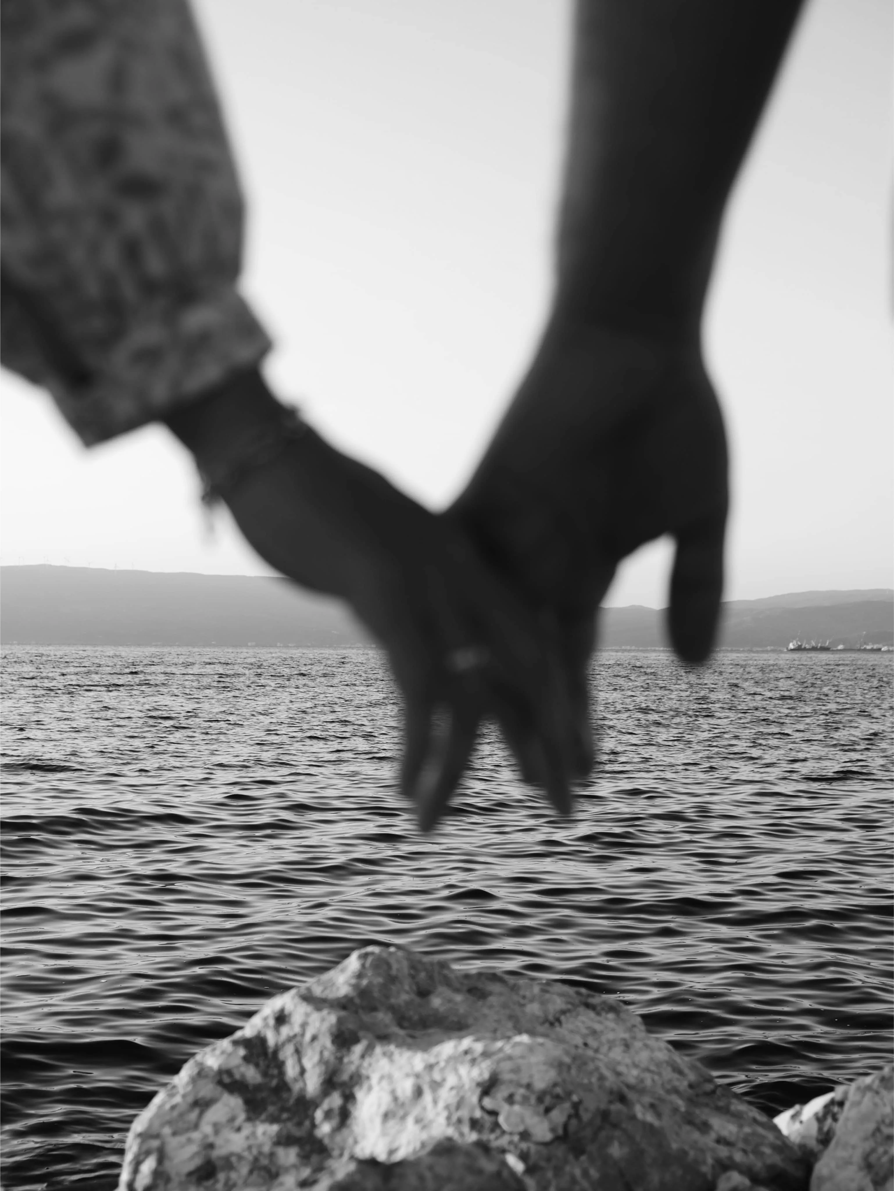 two individuals hands together over a view of the ocean